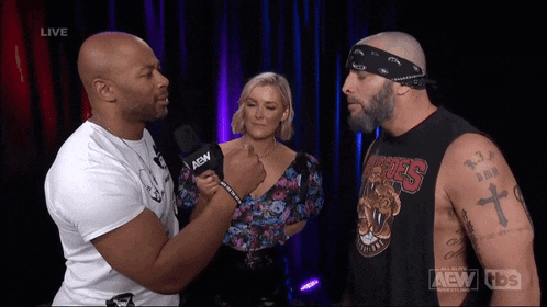 a man with a microphone that says aew on it is talking to another man