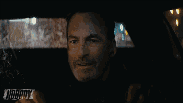 a man sitting in a car with the word nobody on the bottom right