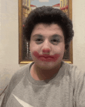 a man with red lipstick on his face is wearing a grey shirt
