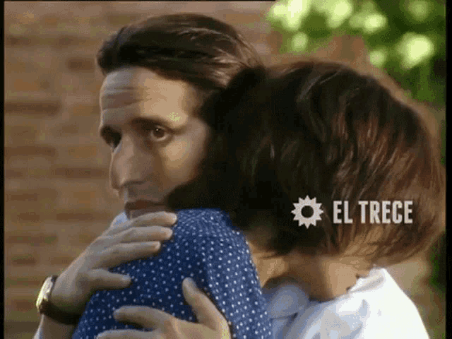 a man is hugging a woman with el trece written on the bottom