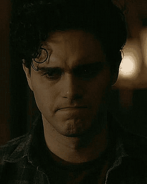 a close up of a man 's face in a dark room with a serious look on his face .