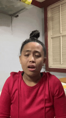 a woman in a red shirt making a funny face with her eyes closed
