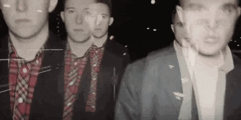 a group of men in suits and plaid shirts are standing next to each other .