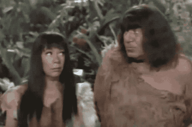 a man and a woman standing next to each other in a forest
