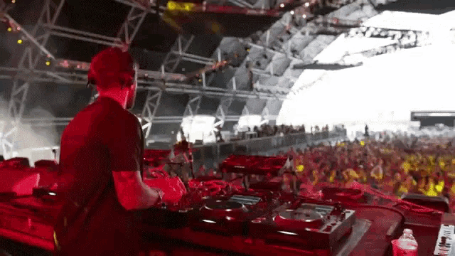 a dj playing music in front of a crowd with a bottle of coca cola on the table