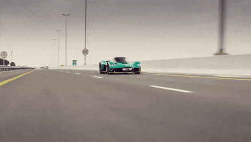 a green sports car is driving down a highway with a sign that says 30
