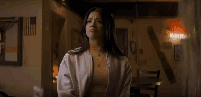 a woman is standing in a room with a table and chairs and looking up .