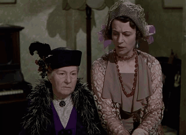two women standing next to each other one wearing a hat