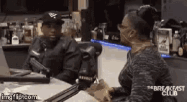 a man and a woman are sitting at a table with a microphone .