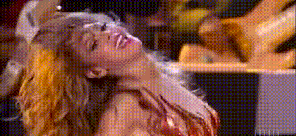 a woman in a red dress is dancing in front of a crowd in a dark room .