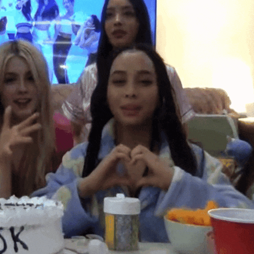 a woman making a heart with her hands in front of a cake that says 5k on it