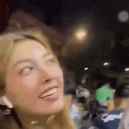 a close up of a woman 's face with a blurry background and a smile on her face .