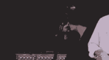 a man is playing a guitar in front of a microphone on a stage in a dark room .