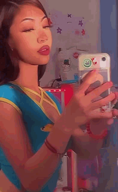 a girl is taking a selfie in front of a mirror with her cell phone .