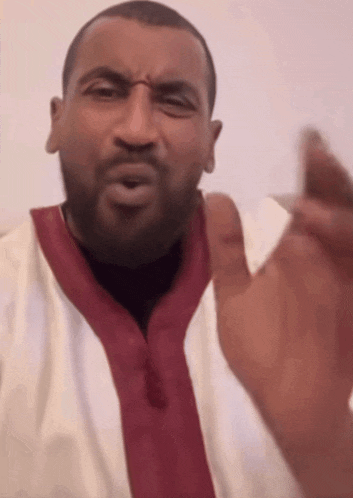 a man with a beard is wearing a white shirt with a red collar