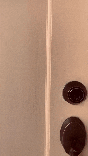 a woman wearing glasses and a pink dress is peeking out of a door
