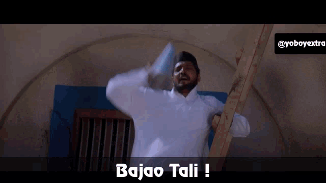 a man in a white shirt is standing on a ladder with the words bajao tali below him