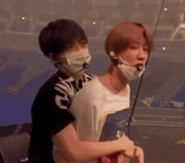 two men wearing masks are hugging each other in a room .