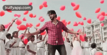 a man in a red plaid shirt is dancing in front of a group of children holding balloons in the shape of hearts .