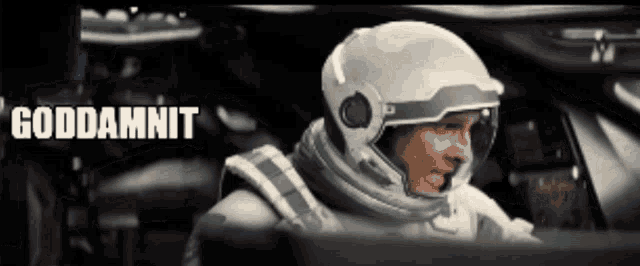 a man in a space suit is sitting in front of a computer screen with the word goddamnit behind him