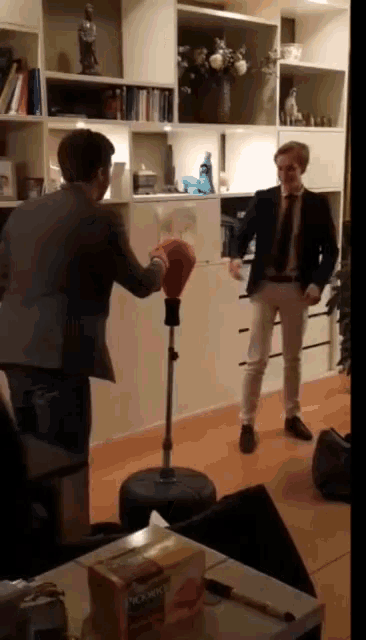 a man wearing boxing gloves stands in front of a punching bag in a living room