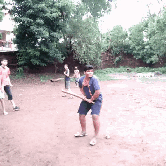 a young boy holding a bat in a dirt field