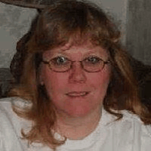 a woman wearing glasses and a white shirt is smiling for a picture .