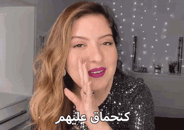 a woman wearing purple lipstick and a sequined top with arabic writing