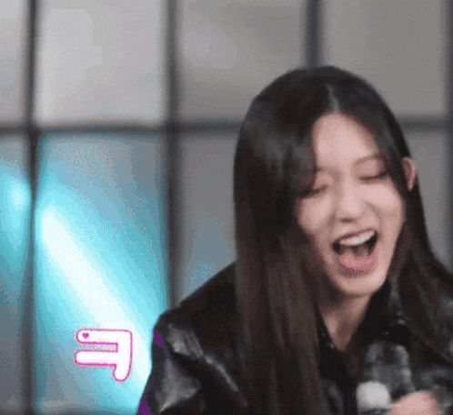 a woman is laughing with her mouth open and a pink letter e is behind her