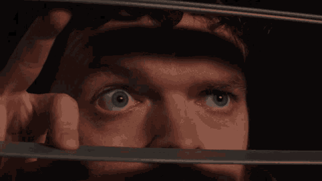 a close up of a man 's eyes looking through a fence