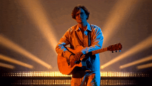 a man is playing an acoustic guitar in front of a crowd