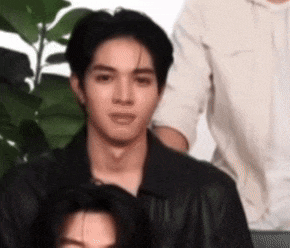a man in a black leather jacket is sitting in front of a group of people .