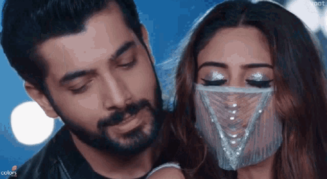 a man with a beard and a woman with a mask on her face are standing next to each other