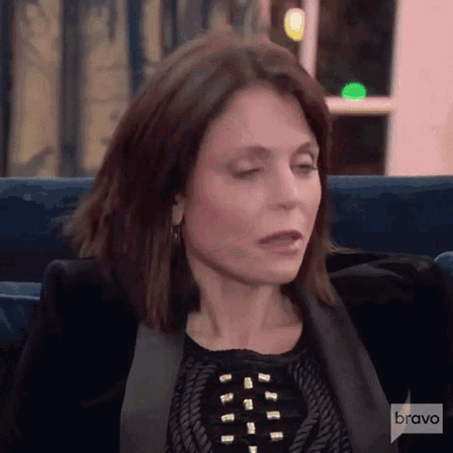 a close up of a woman sitting on a couch with her eyes closed .