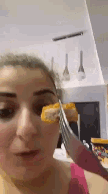 a woman is holding a piece of food in front of her face with a pair of scissors .