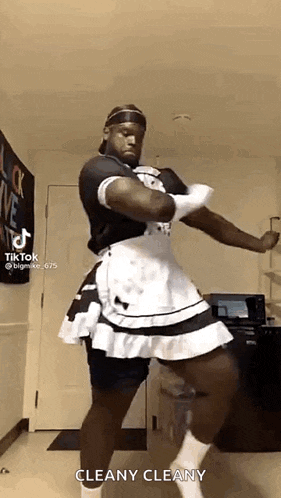 a man is dressed as a maid and dancing in a kitchen .
