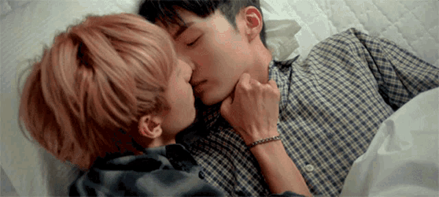 a man and a woman are kissing while laying in bed .