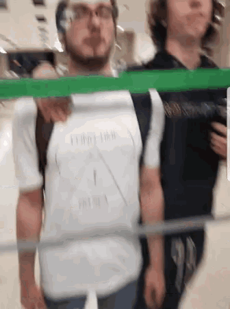 two men are standing next to each other and one of them is wearing a t-shirt that says " i am here "