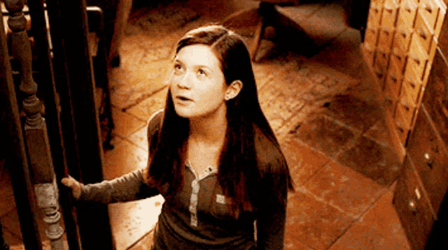 a girl standing in a dark room looking up at the sky