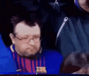 a man with glasses and a beard is wearing a fc barcelona shirt