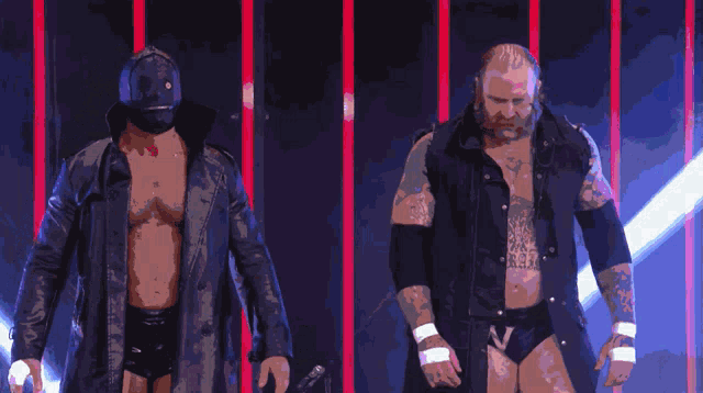two wrestlers are walking in a dark room with a purple background