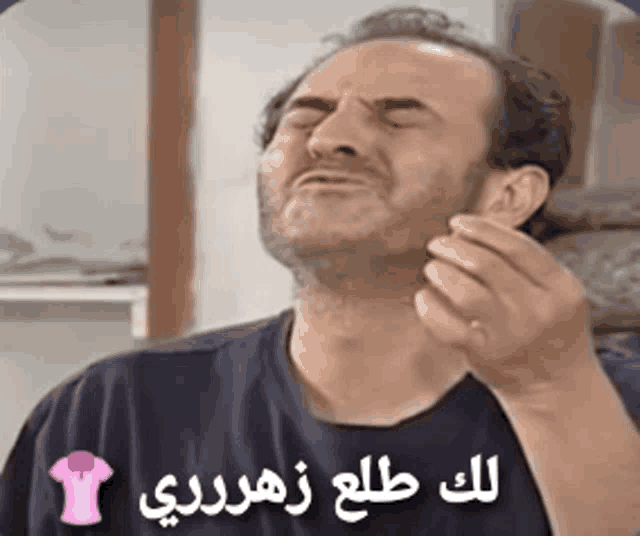 a man in a black shirt is making a funny face with arabic writing on it .