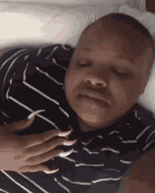 a woman with long pink nails is sleeping in a bed .
