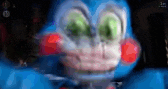 a blue stuffed animal with green eyes and red cheeks is looking at the camera .
