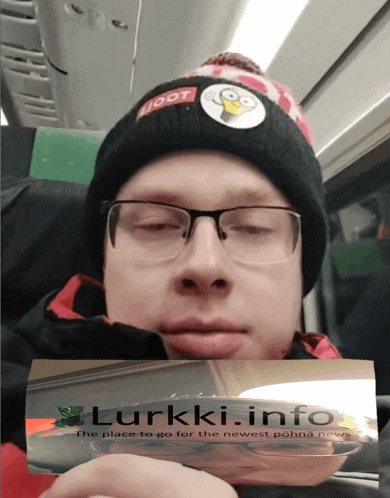 a man wearing a beanie and glasses is holding a piece of paper with lurkki info written on it