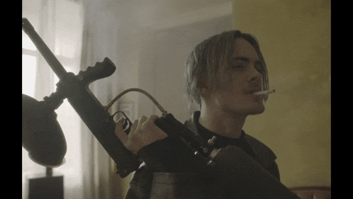 a man smoking a cigarette while holding a gun over his shoulder