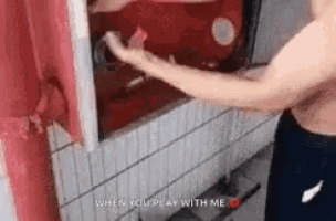 a shirtless man is reaching into a red box with the words `` when you play with me '' written on the bottom .