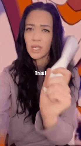 a woman is holding a remote control in her hand with the words treat written on it .
