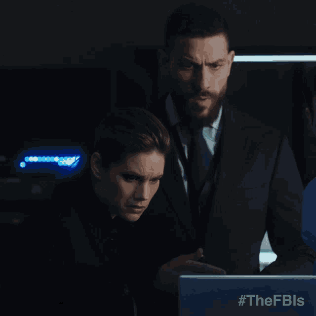 a man and a woman looking at a laptop with #thefbls written on the screen