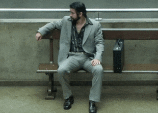 a man in a suit is sitting on a wooden bench